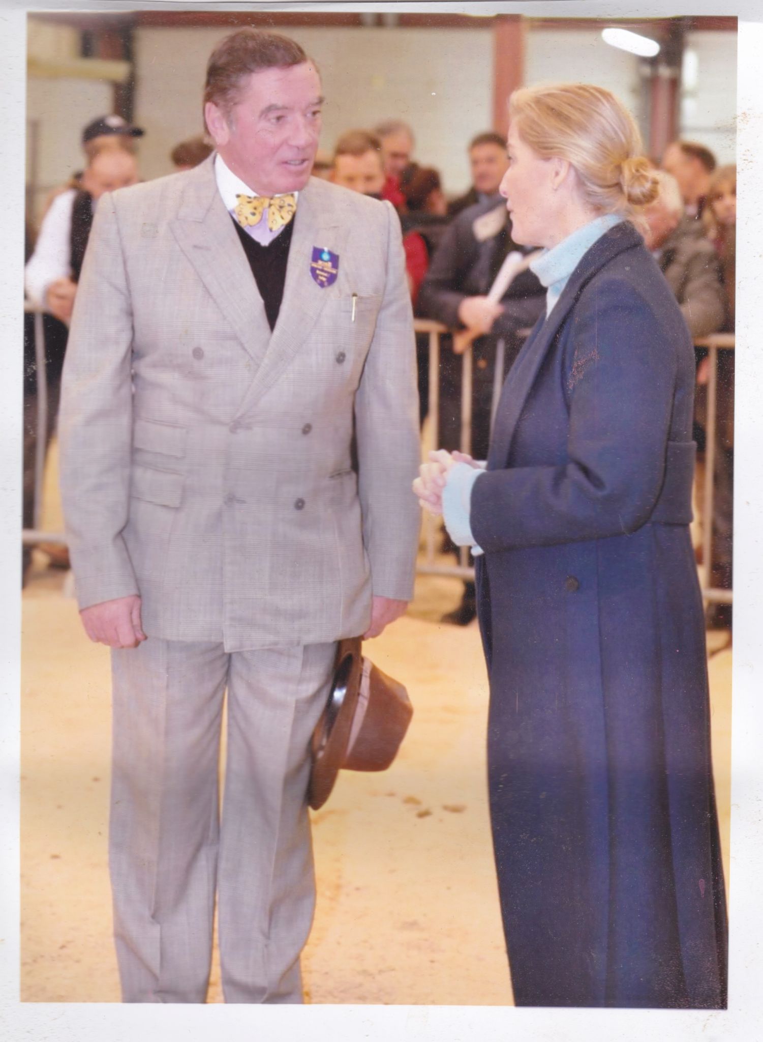 An image of Chris judging at a cattle auction, speaking to a woman.